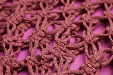 Photo of Handmade macrame shopping bag on crimson background, closeup