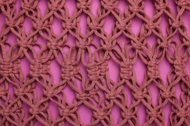 Photo of Handmade macrame shopping bag on crimson background, closeup