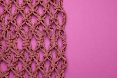 Photo of Handmade macrame shopping bag on crimson background, top view. Space for text