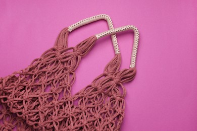 Photo of Handmade macrame shopping bag on crimson background, top view