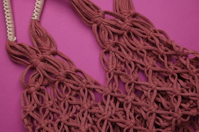 Photo of Handmade macrame shopping bag on crimson background, closeup