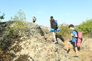 Photo of Family climbing on stones outdoors on sunny day, back view