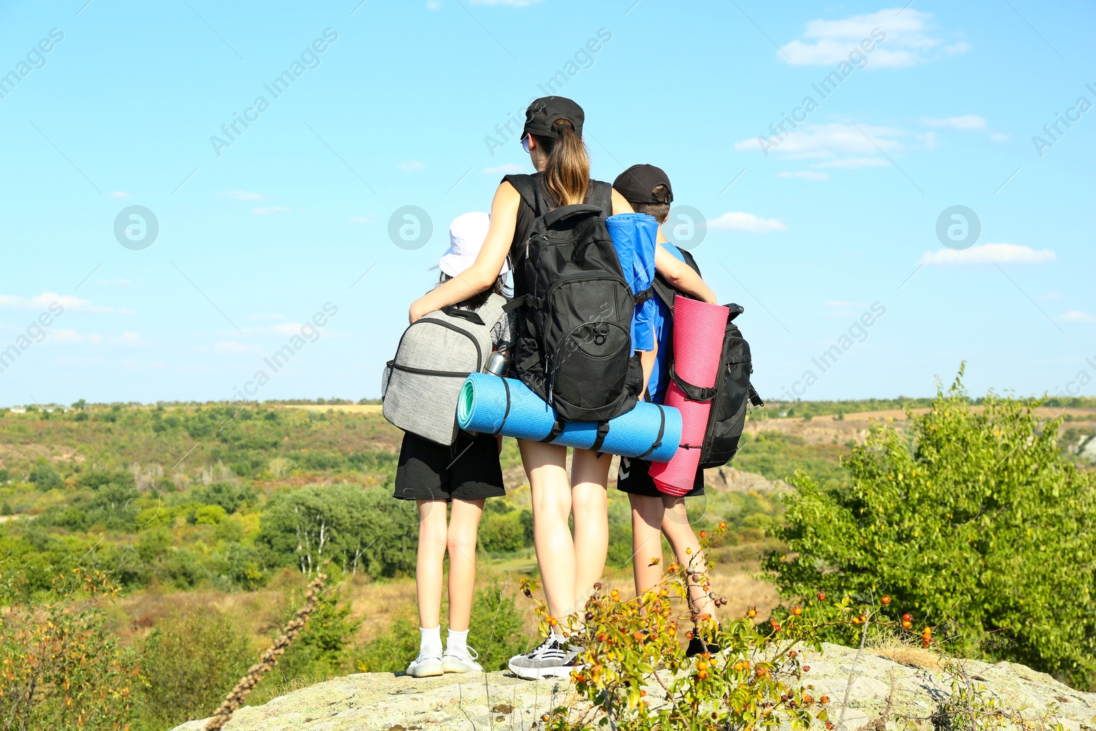 Photo of Family of tourists with backpacks enjoying picturesque landscape, back view