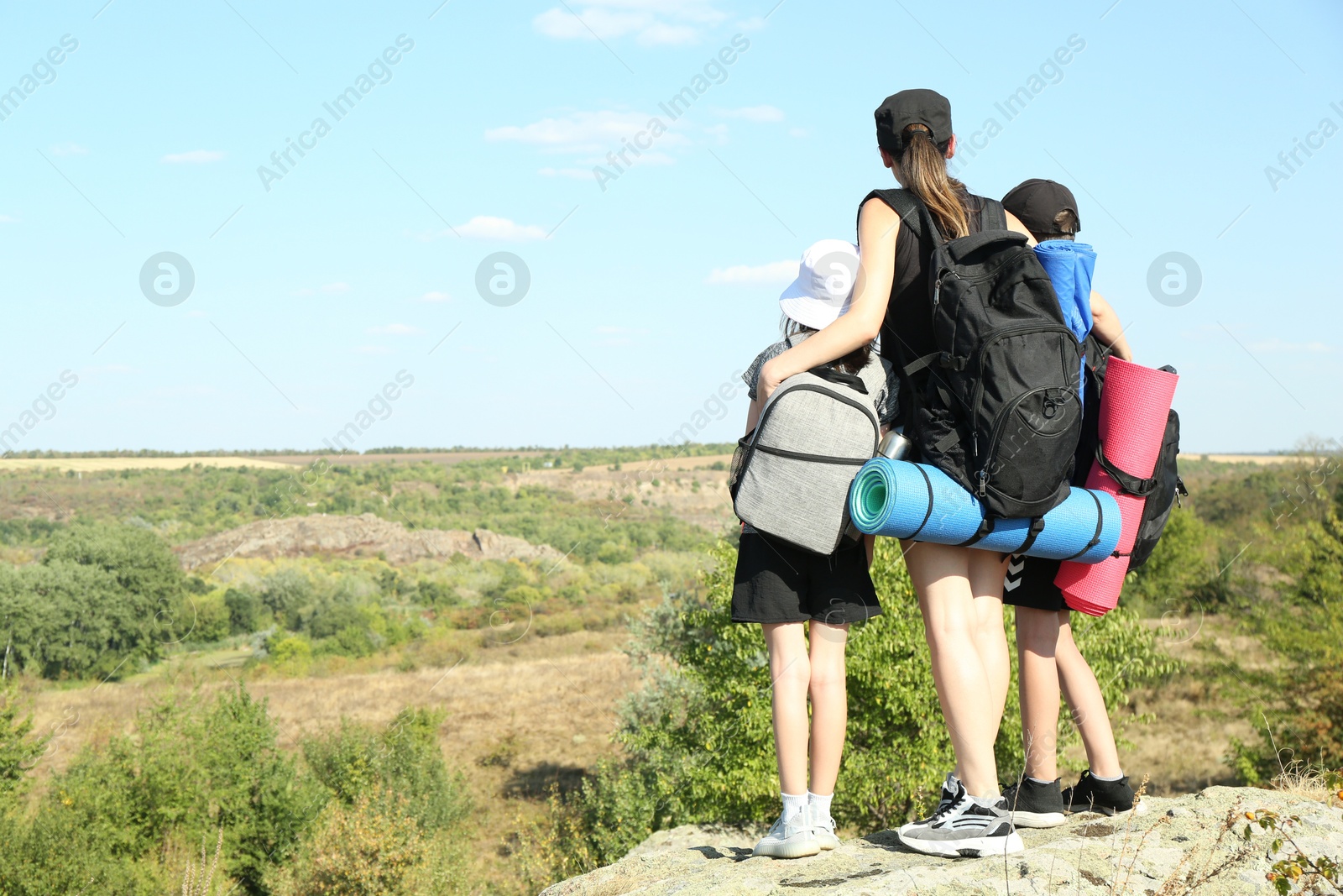 Photo of Family of tourists with backpacks enjoying picturesque landscape, back view. Space for text