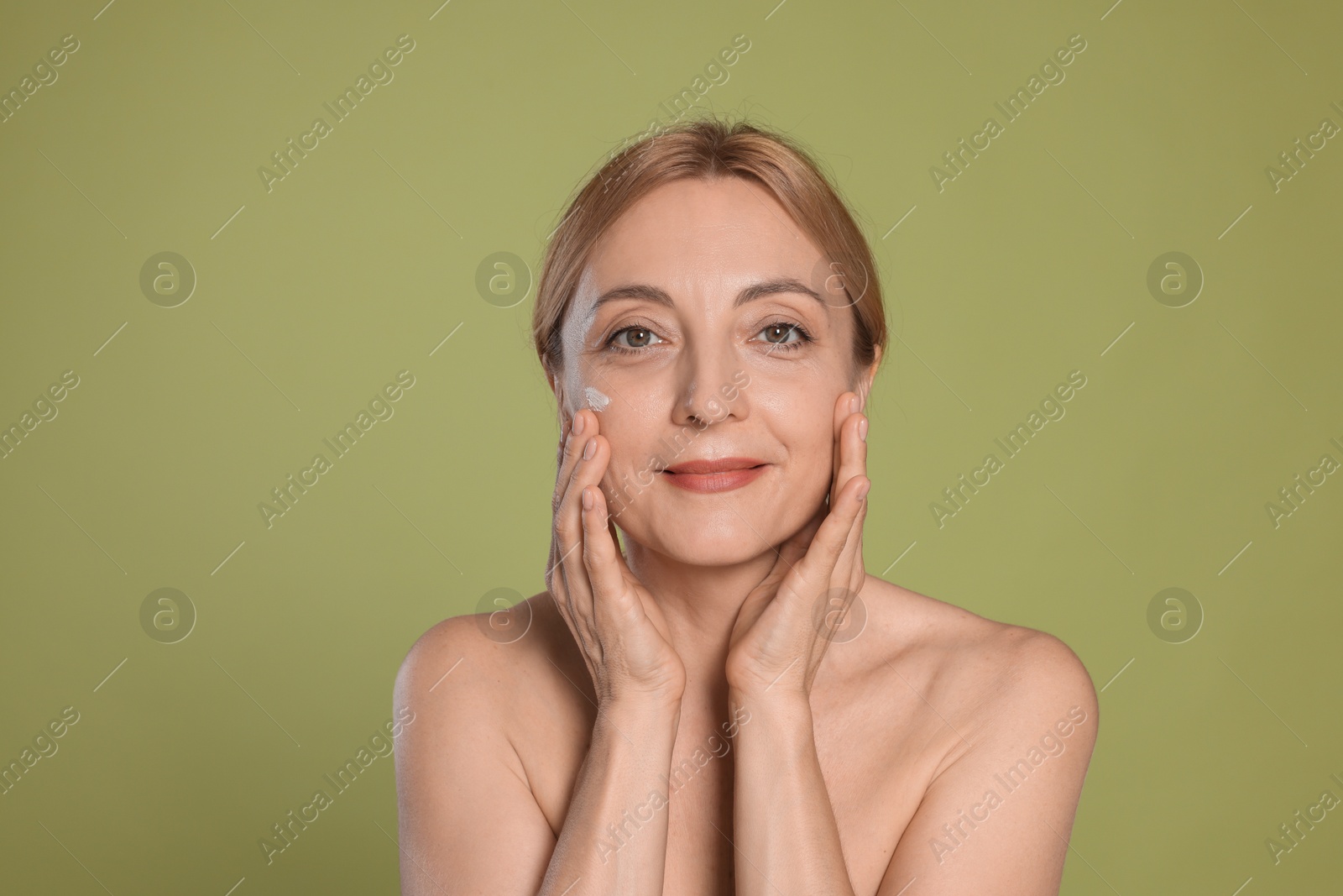 Photo of Portrait of beautiful woman with cream on face on green background