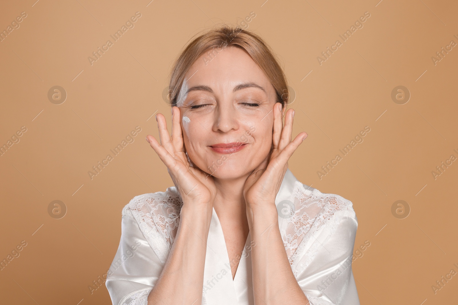 Photo of Beautiful woman with cream on face against beige background