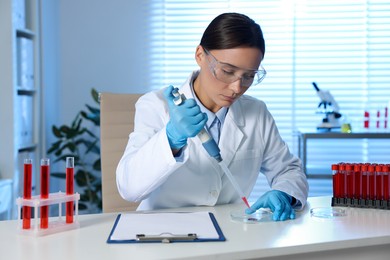 Photo of Laboratory testing. Doctor dripping blood sample into Petri dish at table indoors