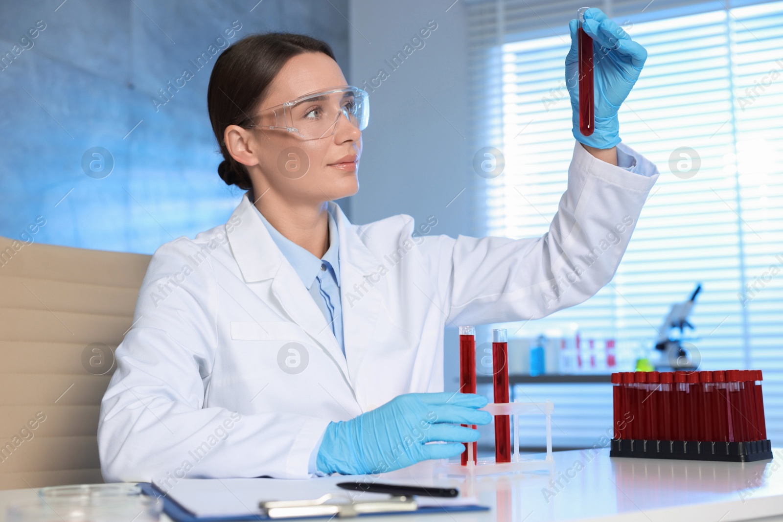 Photo of Laboratory testing. Doctor holding test tube with blood sample at table indoors