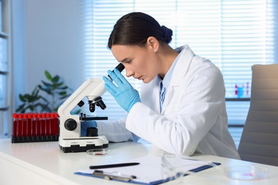 Photo of Laboratory testing. Doctor working with microscope at table indoors