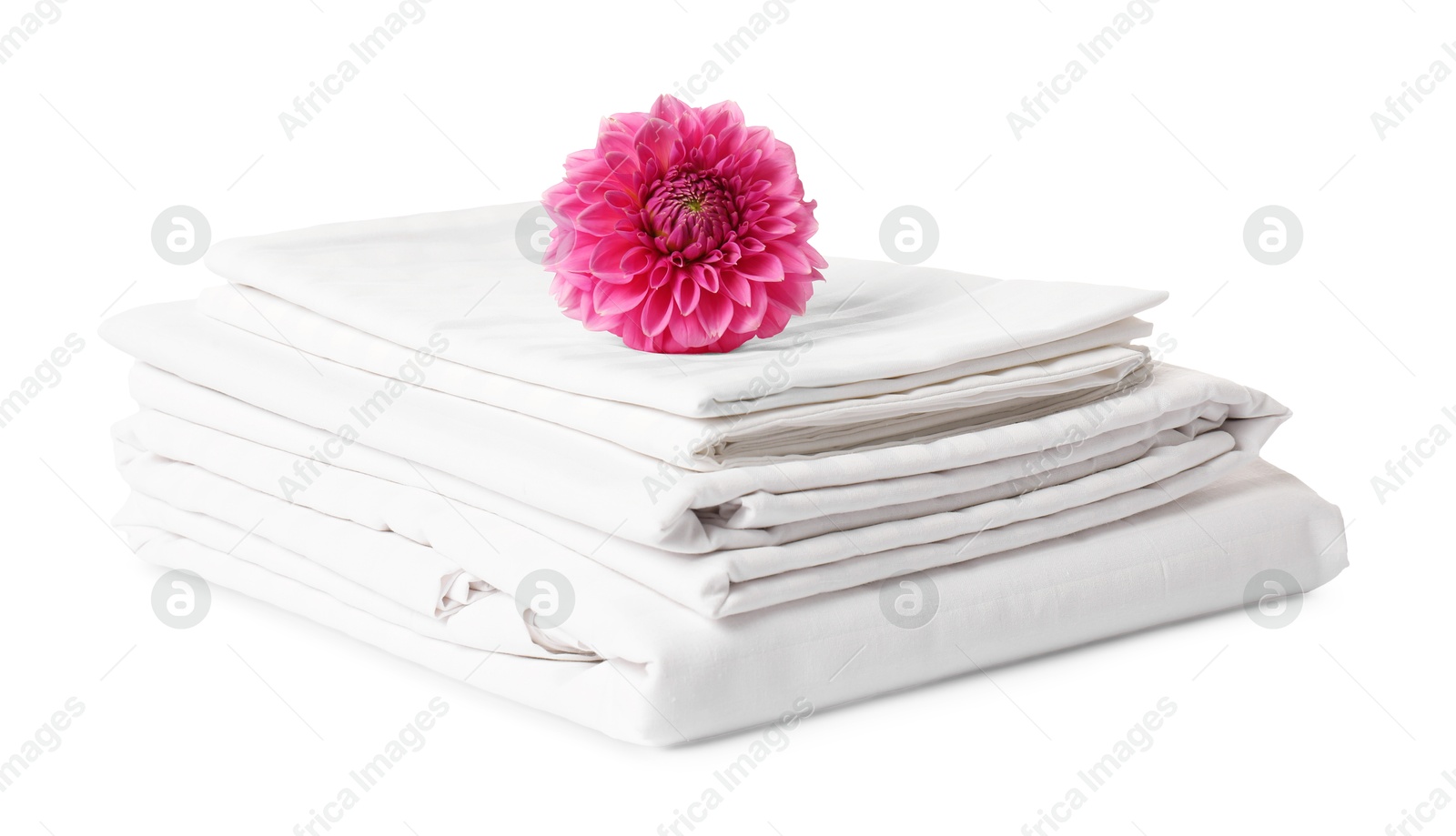 Photo of Stacked bed linens and pink flower on white background