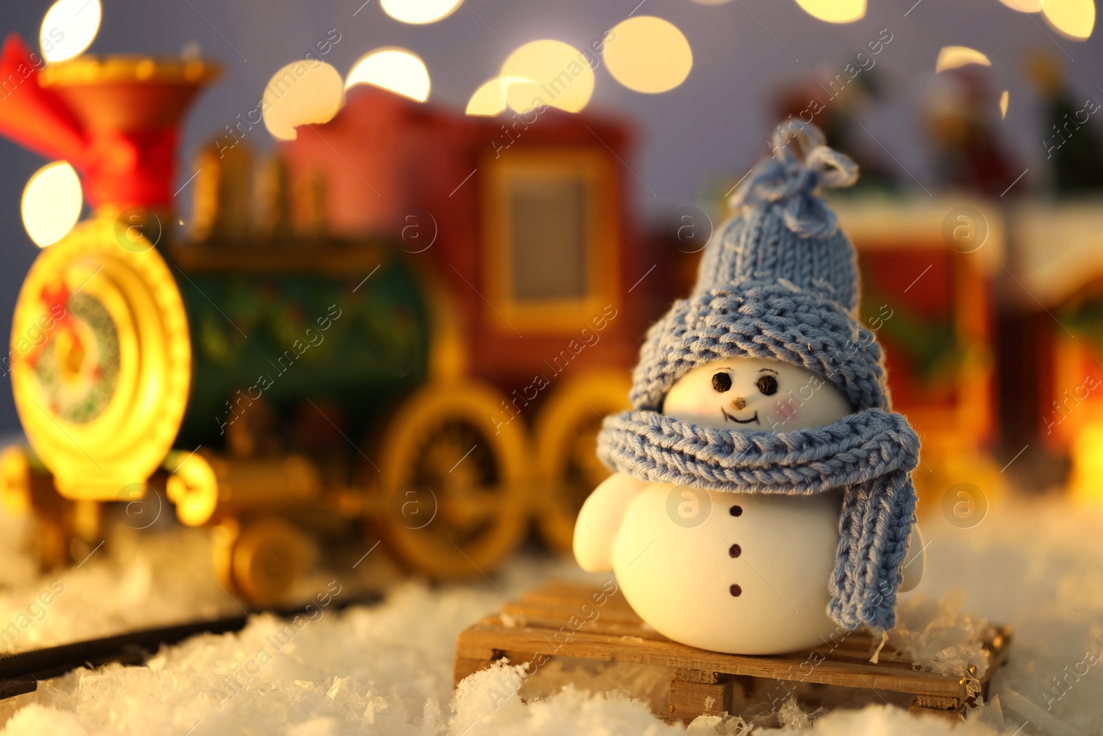 Photo of Cute decorative snowman on artificial snow against blurred background, closeup