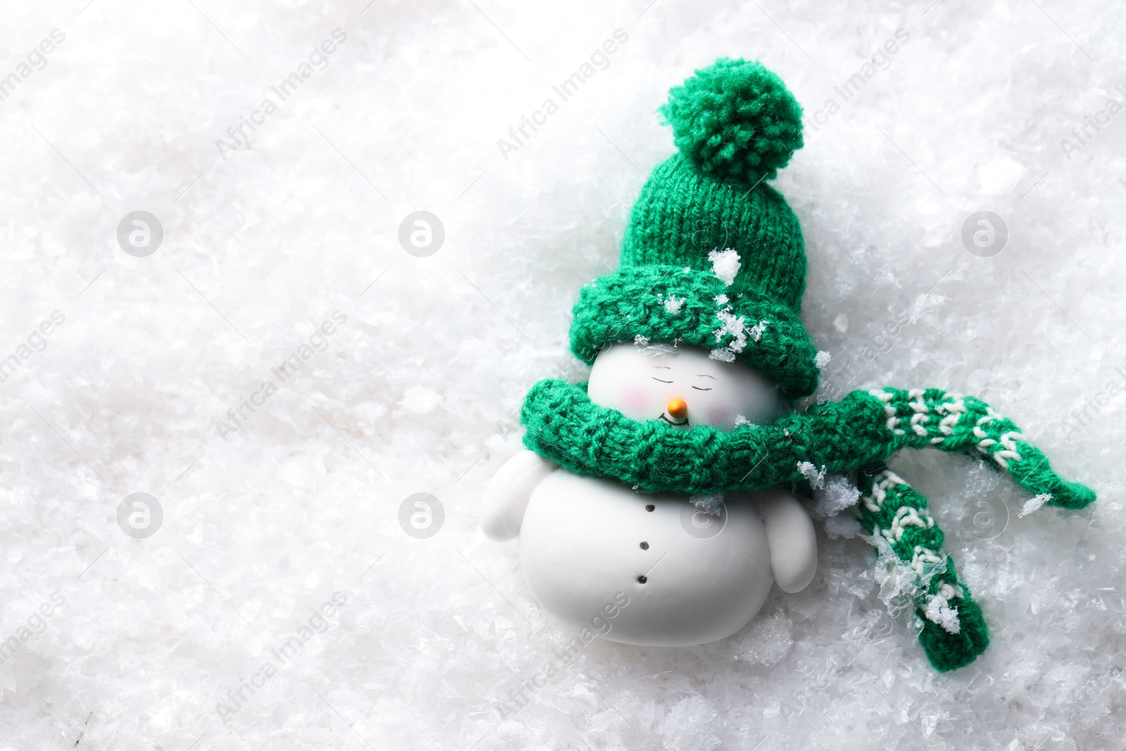 Photo of Cute decorative snowman on artificial snow, top view. Space for text