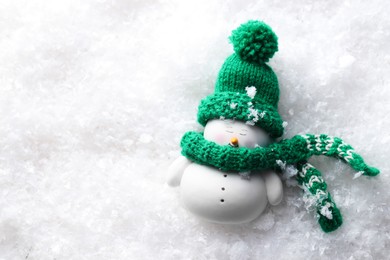 Photo of Cute decorative snowman on artificial snow, top view. Space for text