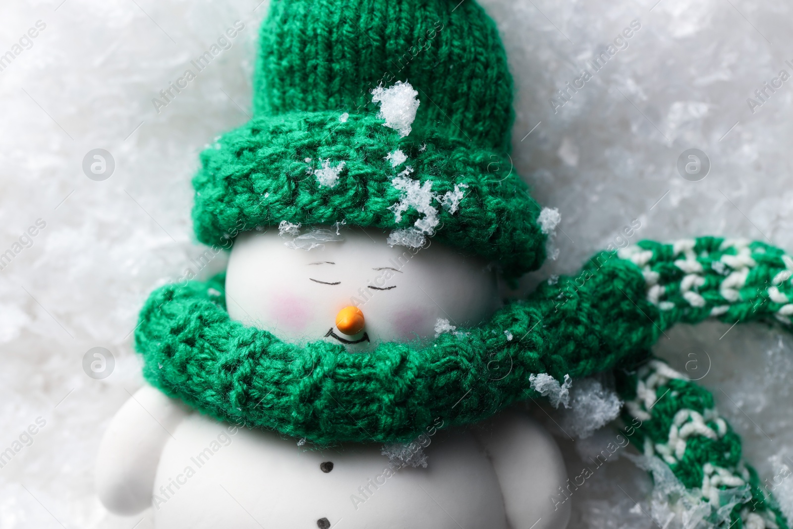 Photo of Cute decorative snowman on artificial snow, top view