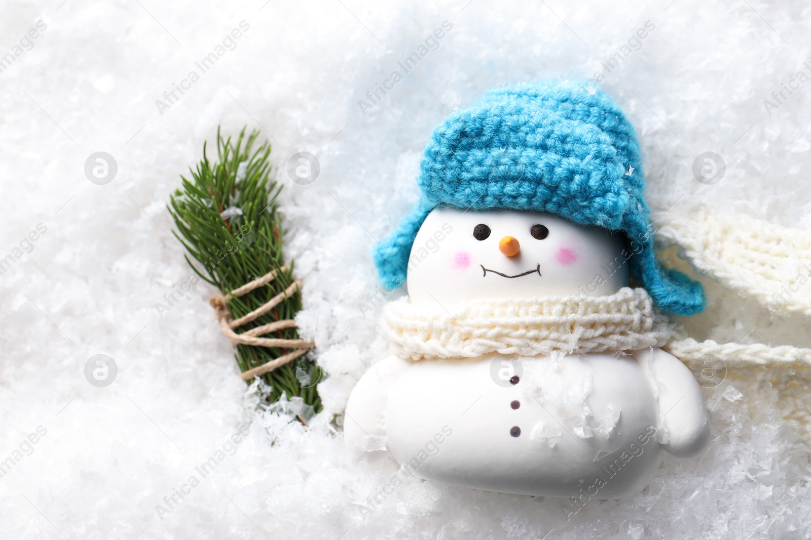 Photo of Cute decorative snowman and fir tree branches on artificial snow, flat lay