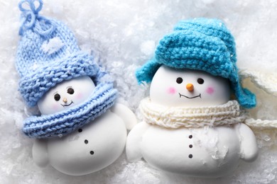 Photo of Cute decorative snowmen on artificial snow, top view