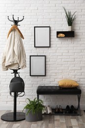 Photo of Stylish hallway interior with coat rack and bench