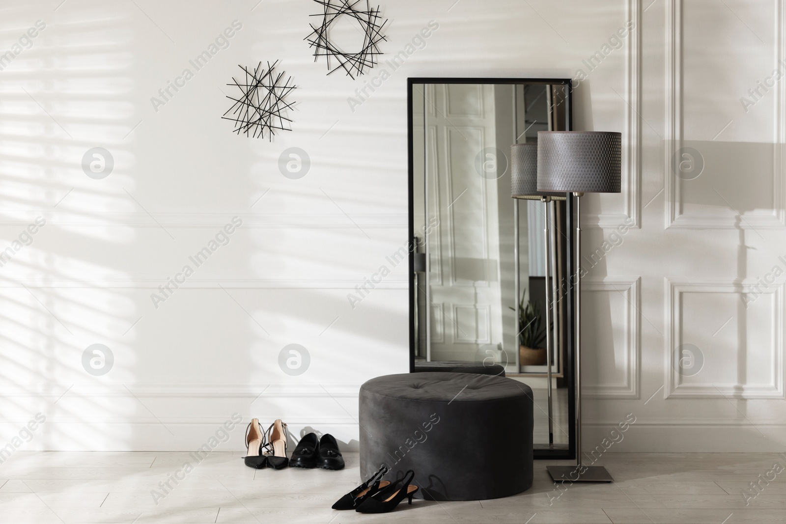 Photo of Stylish hallway interior with mirror, lamp and pouffe