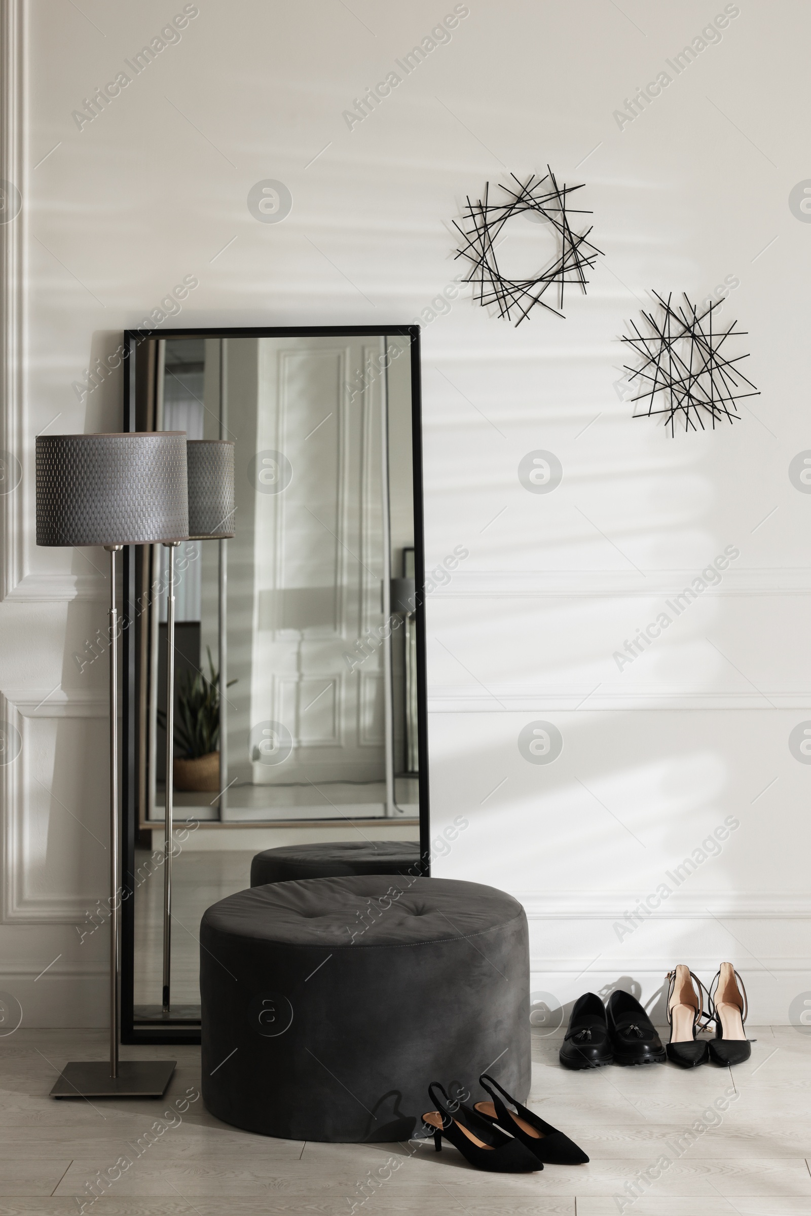 Photo of Stylish hallway interior with mirror, lamp and pouffe