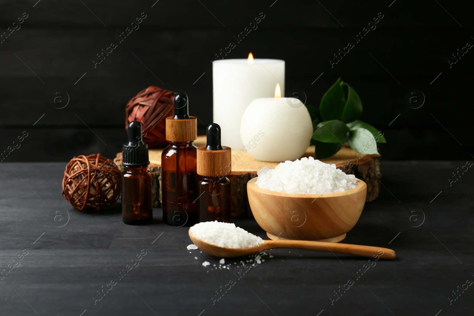 Photo of Composition with cosmetic products and candles for spa treatment on black wooden table