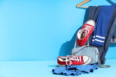 Photo of Clothes, shoes and bag on light blue background, space for text