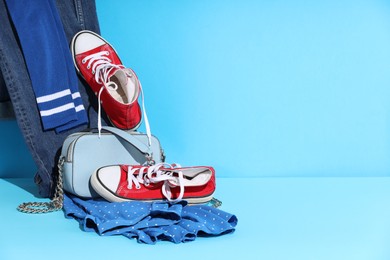 Photo of Clothes, shoes and bag on light blue background, space for text