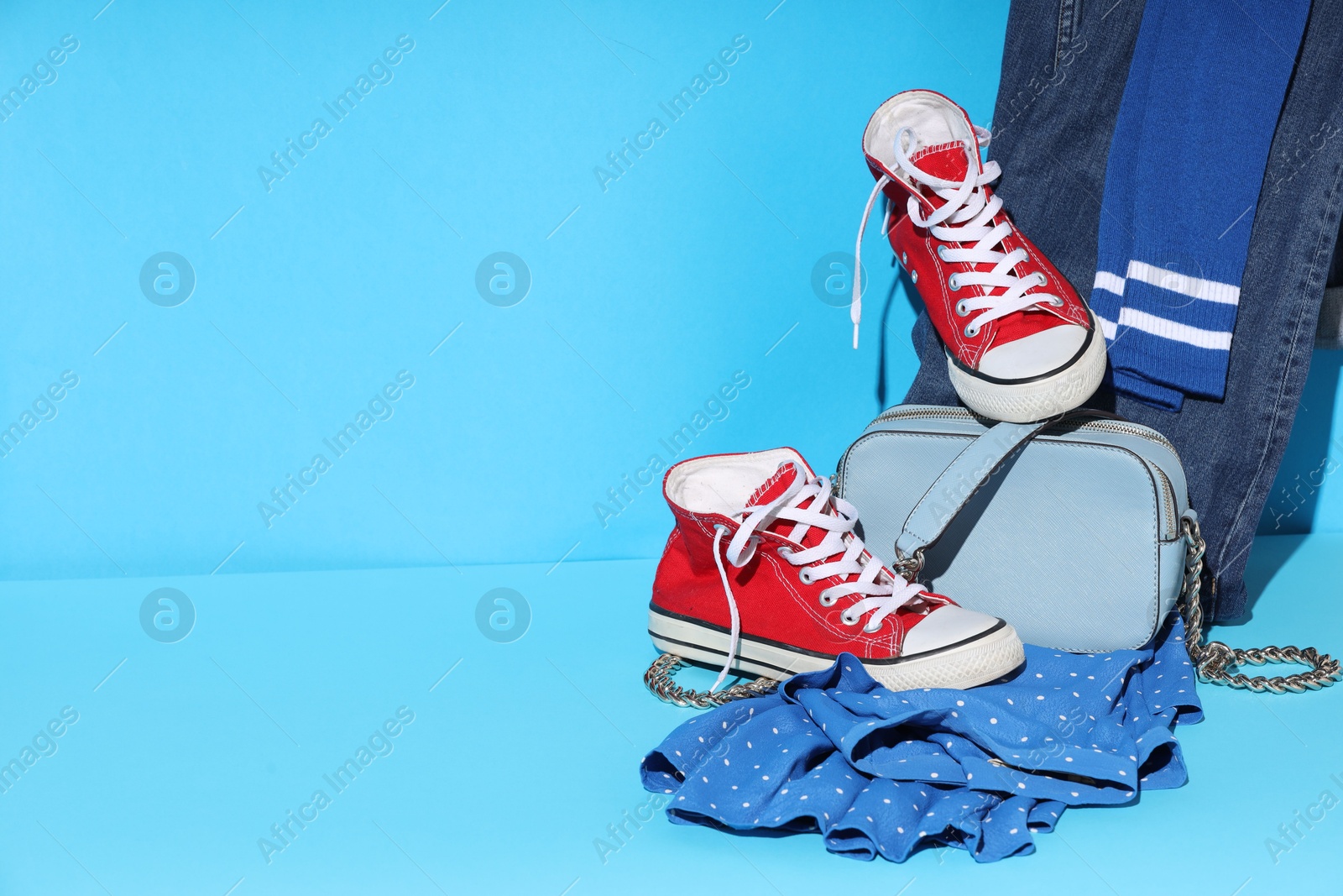 Photo of Clothes, shoes and bag on light blue background, space for text