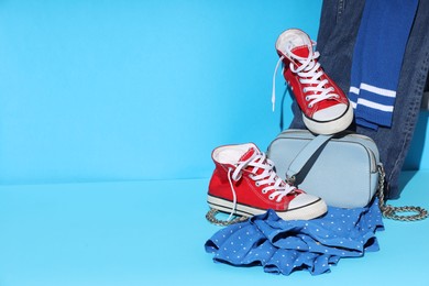 Photo of Clothes, shoes and bag on light blue background, space for text