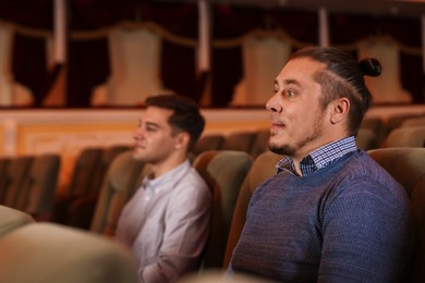 Two men watching theatrical performance in theatre