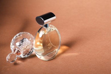 Photo of Bottles of perfume on brown background, space for text