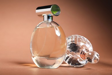 Photo of Bottles of fragrant perfume on brown background, closeup