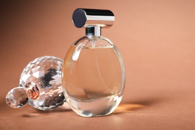 Photo of Bottles of perfume on brown background, closeup. Space for text