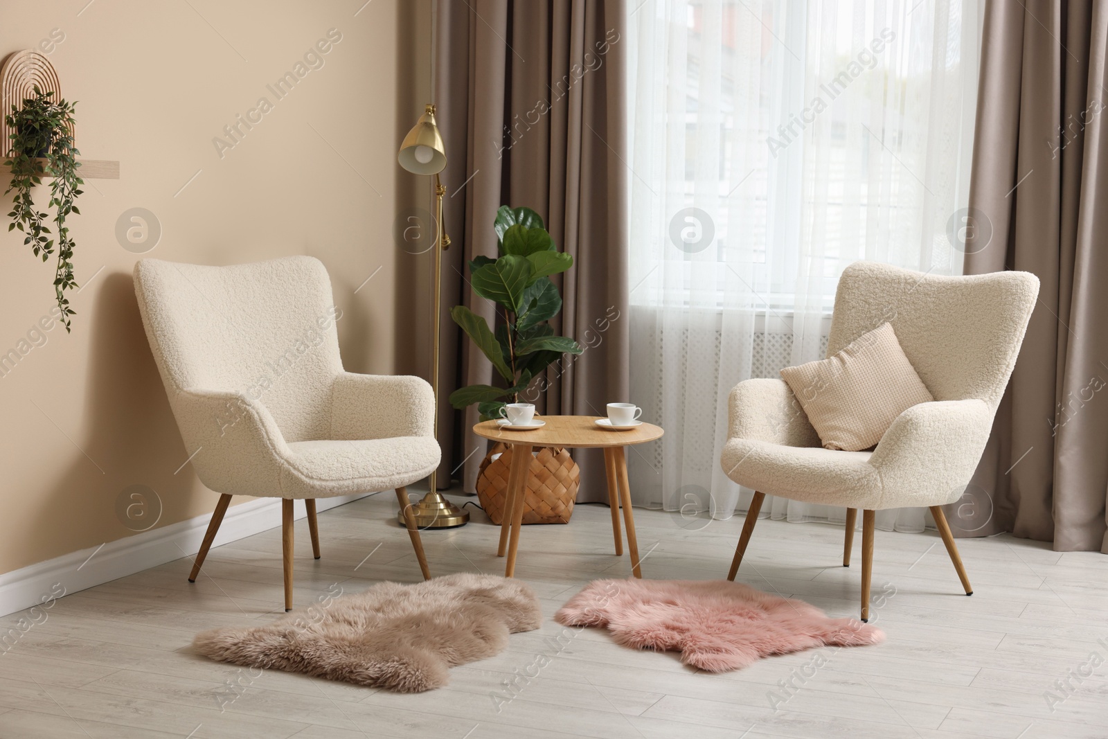 Photo of Soft armchairs and coffee table near beige wall indoors