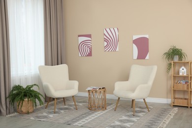 Photo of Soft armchairs and coffee table near beige wall indoors