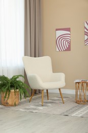 Photo of Soft armchair near beige wall at home