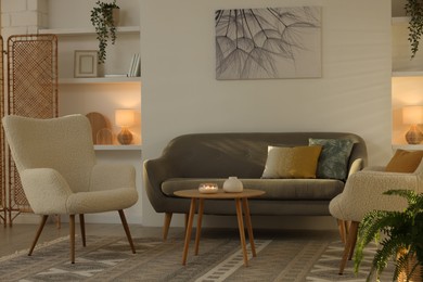 Photo of Beautiful armchairs, sofa and coffee table in living room. Interior design