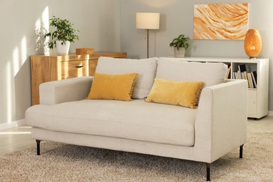 Photo of Stylish living room interior with soft sofa and chest of drawers near grey wall