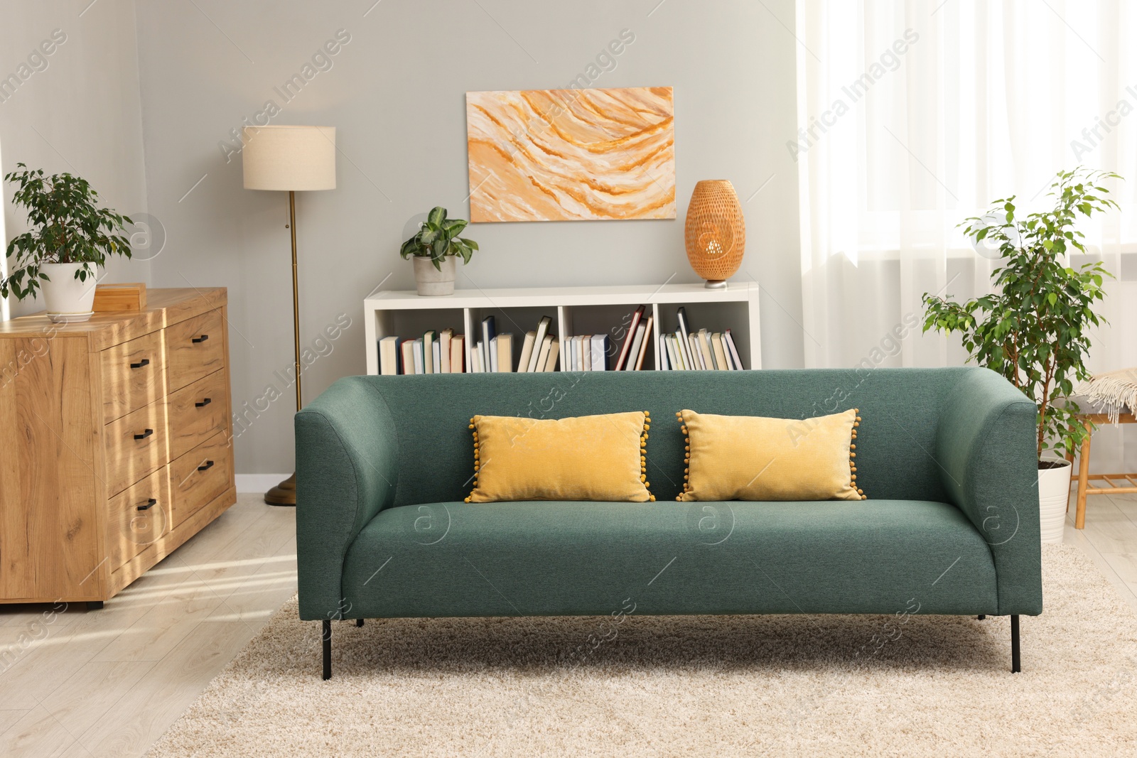 Photo of Stylish living room interior with soft sofa and chest of drawers near grey wall