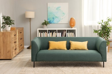 Photo of Stylish living room interior with soft sofa and chest of drawers near grey wall