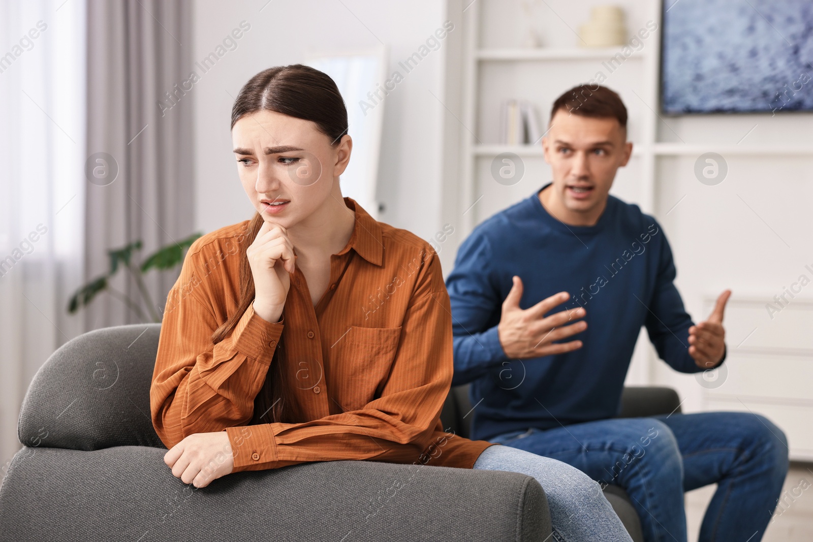 Photo of Upset woman ignoring her husband at home, selective focus