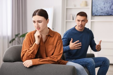 Photo of Upset woman ignoring her husband at home, selective focus