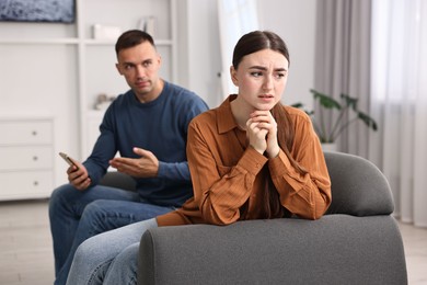 Upset woman ignoring her husband at home, selective focus