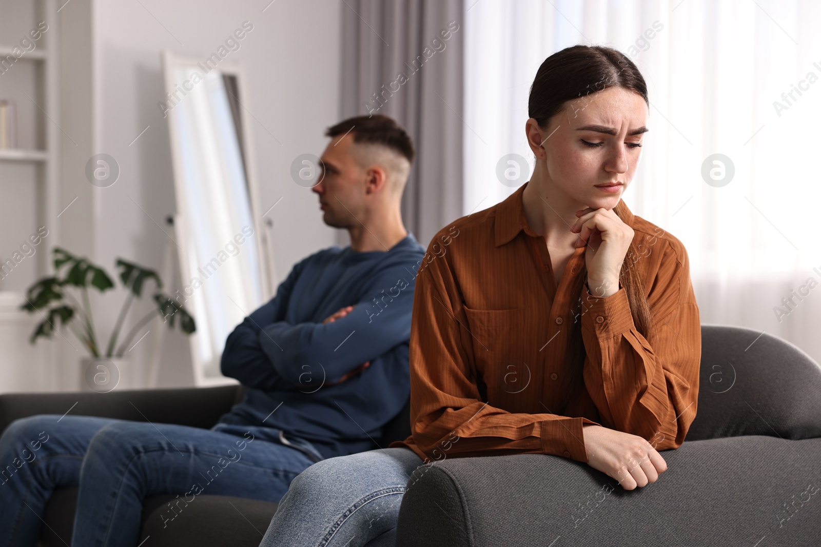 Photo of Offended couple ignoring each other at home, selective focus