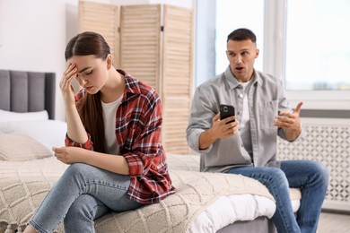 Upset woman ignoring her husband at home, selective focus