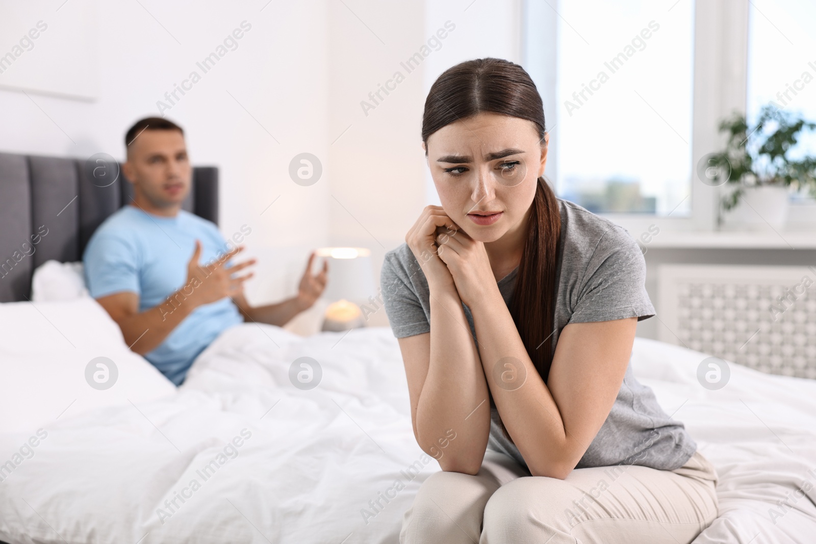 Photo of Upset woman ignoring her husband in bedroom, selective focus