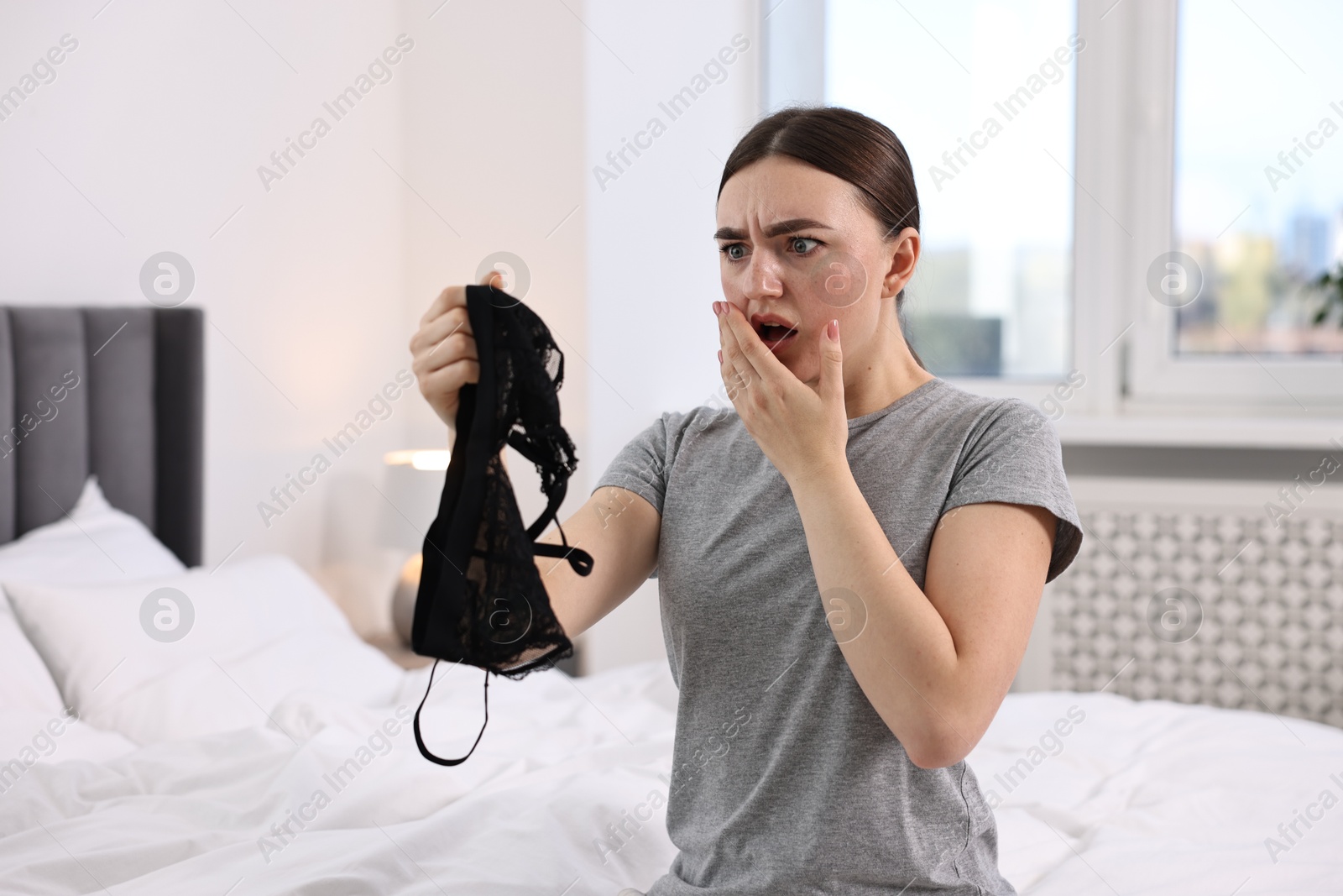 Photo of Surprised wife finding mistress bra in bedroom