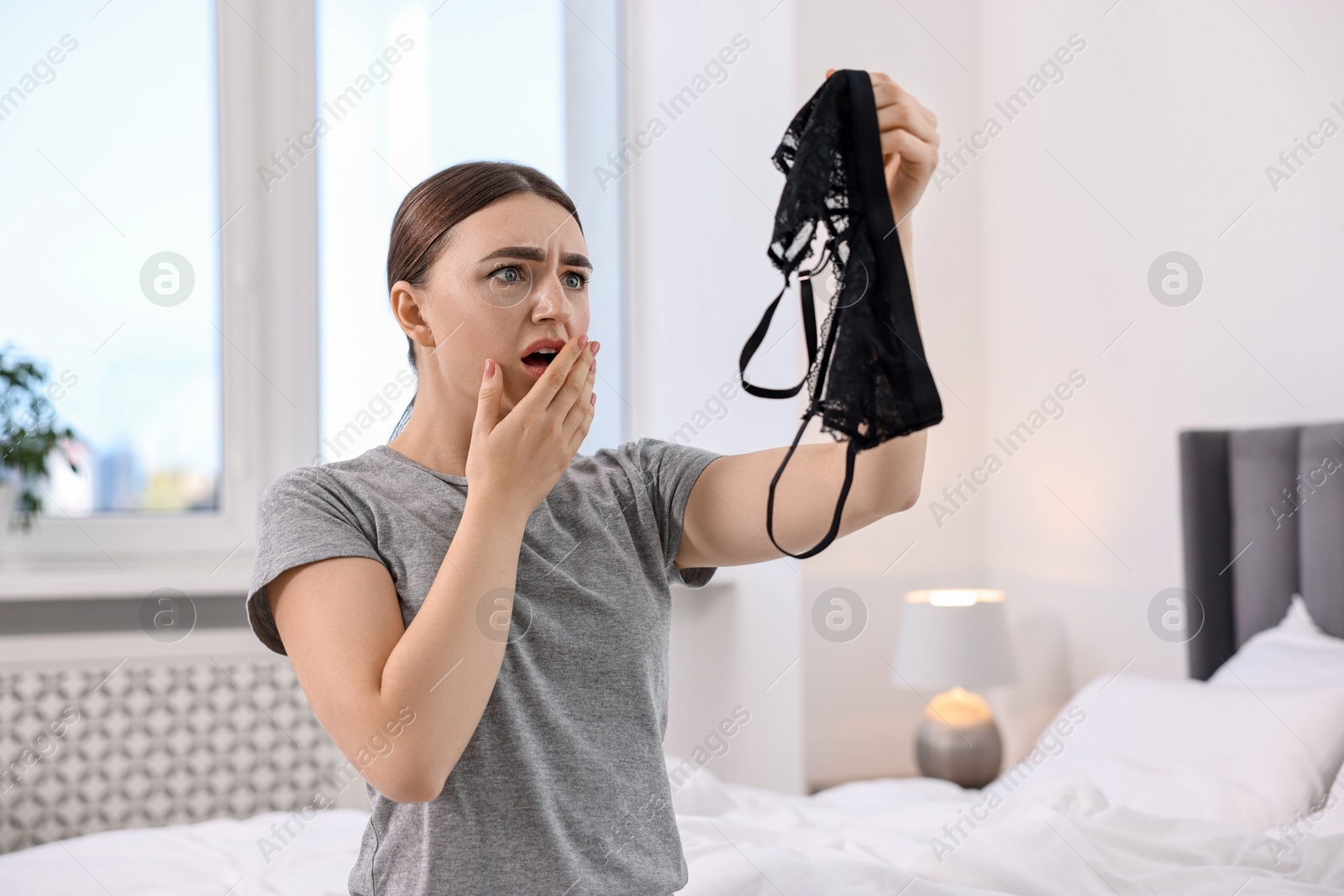 Photo of Surprised wife finding mistress bra in bedroom