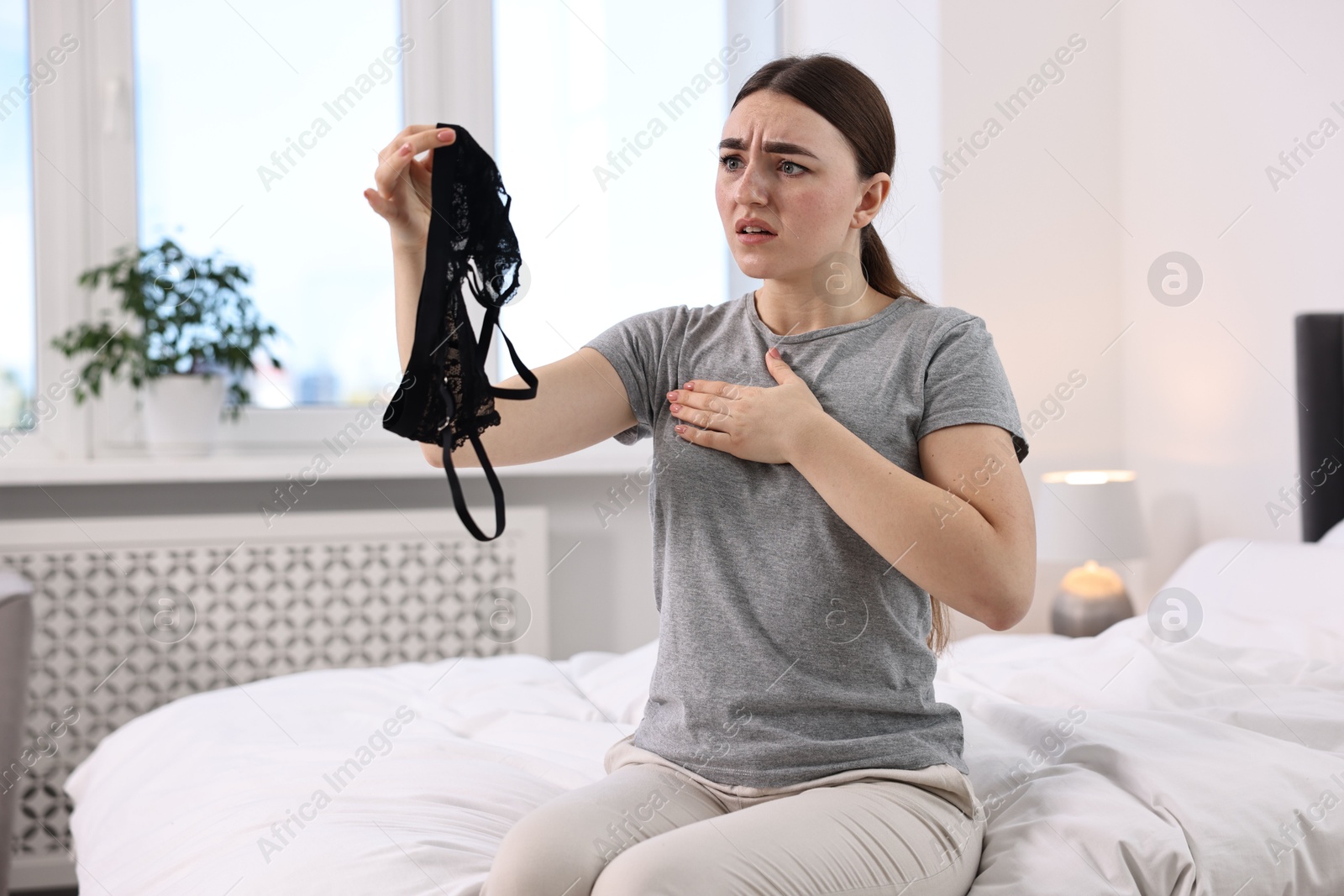 Photo of Frustrated wife finding mistress bra in bedroom