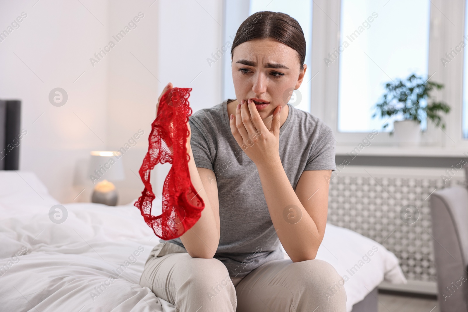 Photo of Frustrated wife finding mistress panties in bedroom