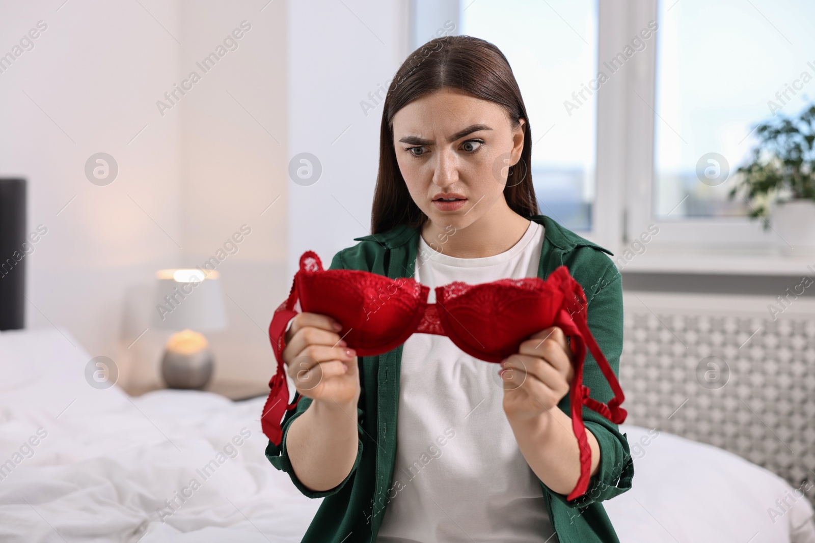 Photo of Surprised wife finding mistress bra in bedroom